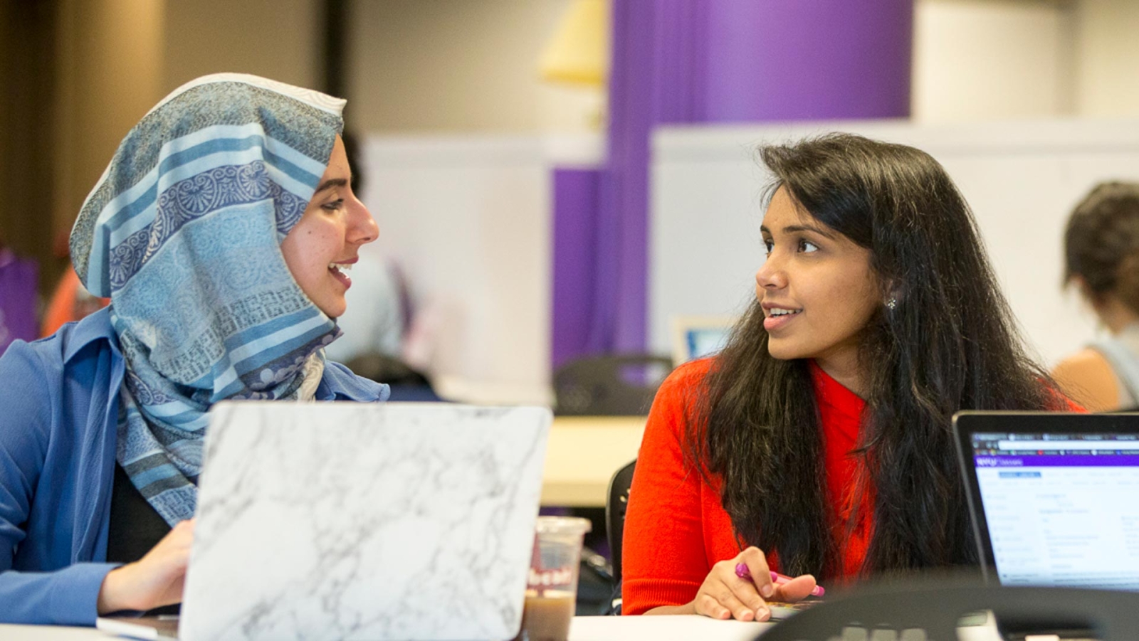 Students talking at a table with laptop computers