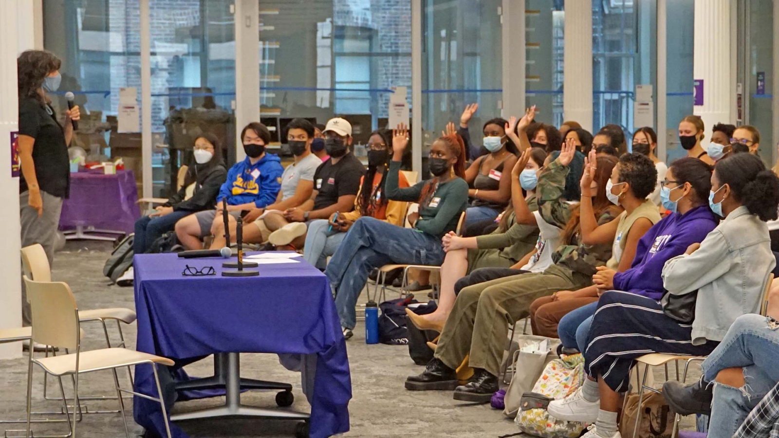 Students sitting in rows at an event raising their hands