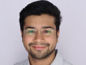 Headshot of Camilo. He is wearing a striped shirt and he is standing in front of a white background.