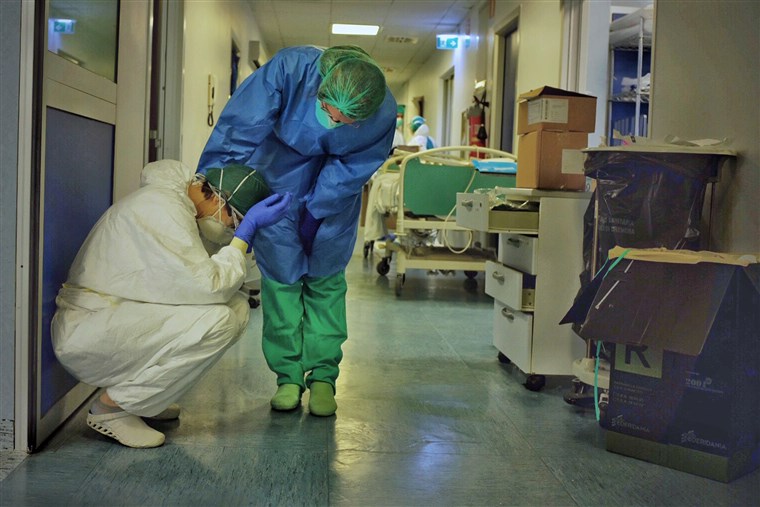 Two intensive care professionals comfort each other in the ICU of a hospital in Cremona, Italy, on Friday, March 13, 2020. Photo by Paolo Miranda