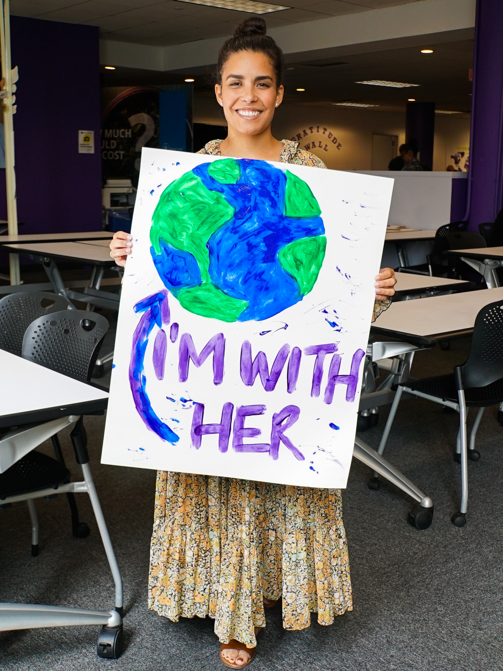 Student holding "I'm With Her" poster