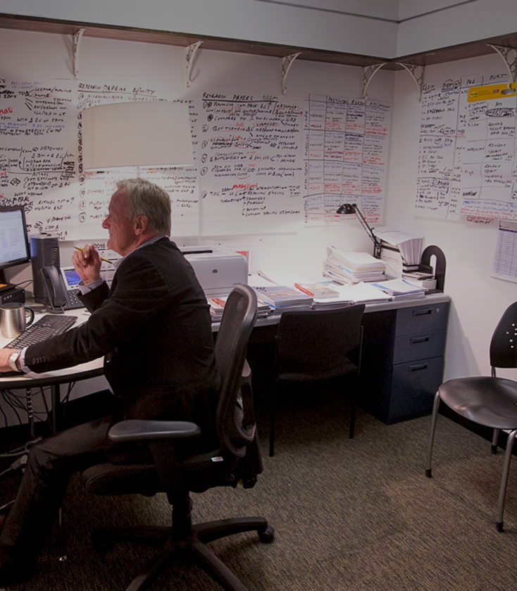 Man sitting at a desk with notes on the wall