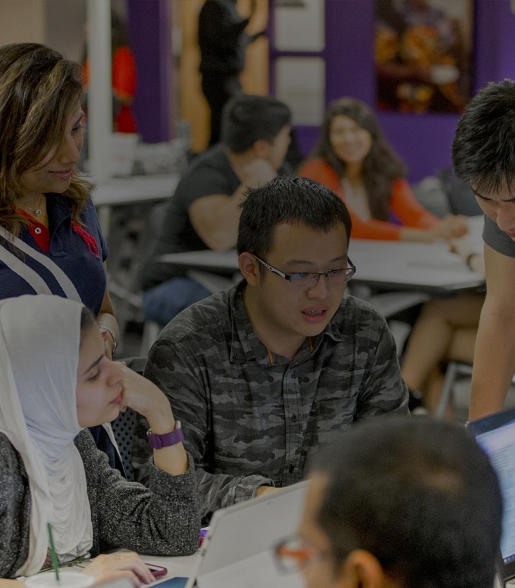 Students gathering around a table with laptops