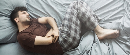 Man curled up in pain in bed