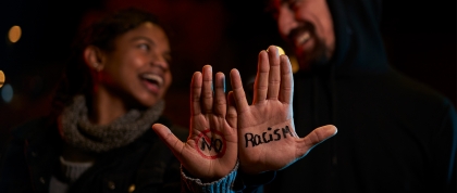 Two people holding up sign saying "No Racism"