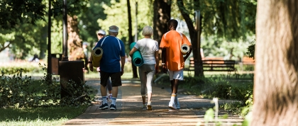 Three people walking in the park with yoga mats