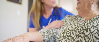 older overweight woman sits on couch with health care provider